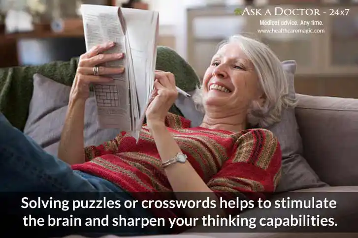 old happy woamn lying of sofa solving crossword in a newspaper