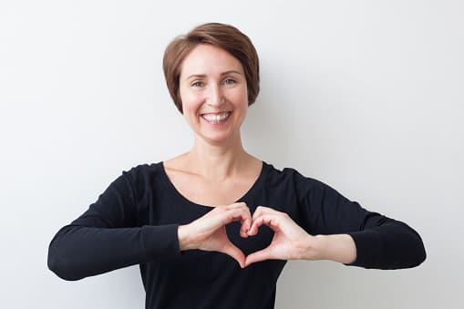 happy and healthy mid-age woman making a heart with her hands