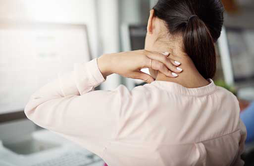 young woman at her work desk feeling slight pain in her neck