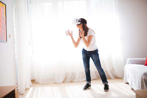 young woman feeling animated while playing with virtual reality glasses