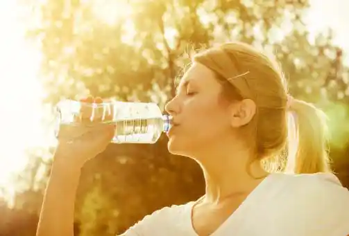 young woman drinking water in sun