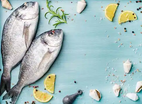 fish on a wooden backgroud with lemon pieces decorated around